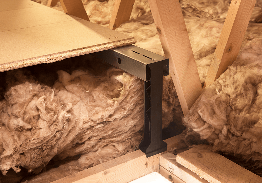 A close up of an attic floor board built on top of insulation, using a raised flooring system.