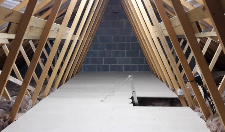 A fully boarded attic with an access hatch and ladder.