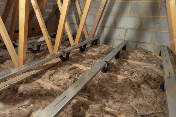 An attic with floor insulation and floor-heightening brackets attached to it.